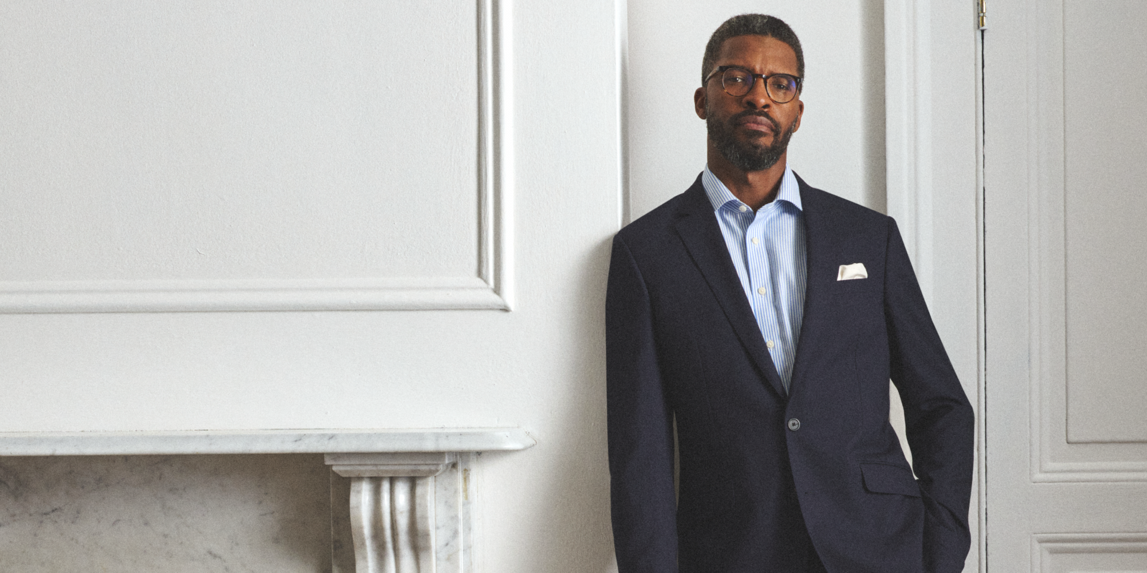 Man in a suit standing against a white wall
