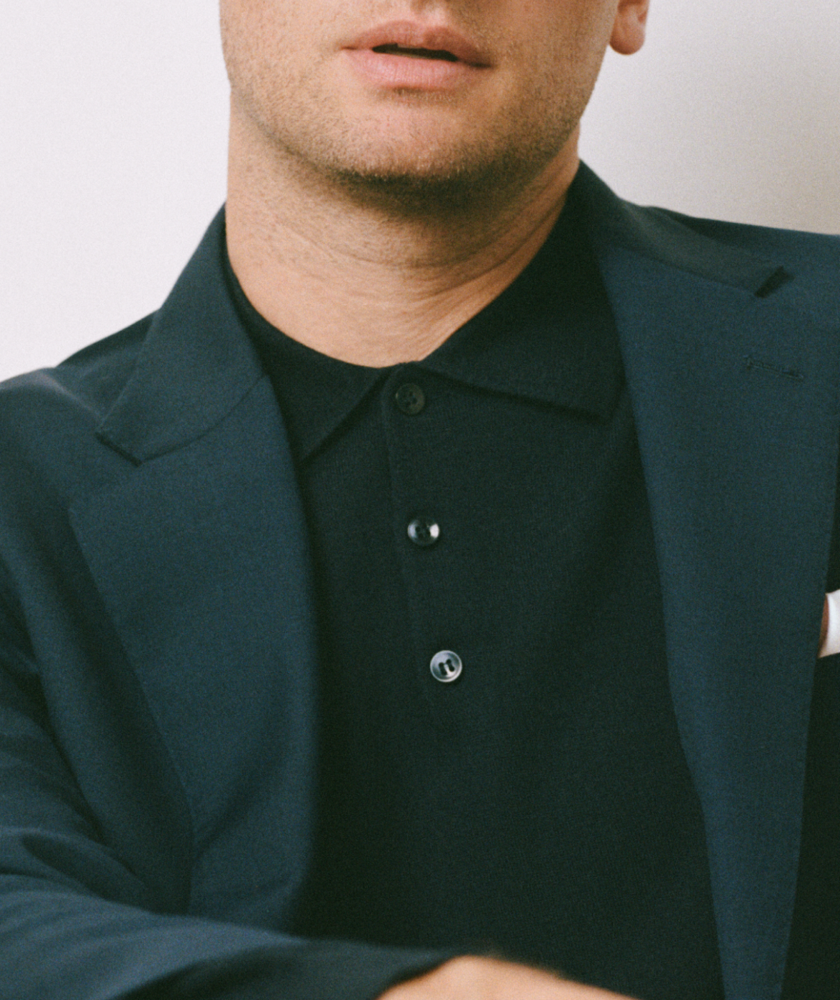 Man wearing a blue jacket over a black buttoned up polo shirt