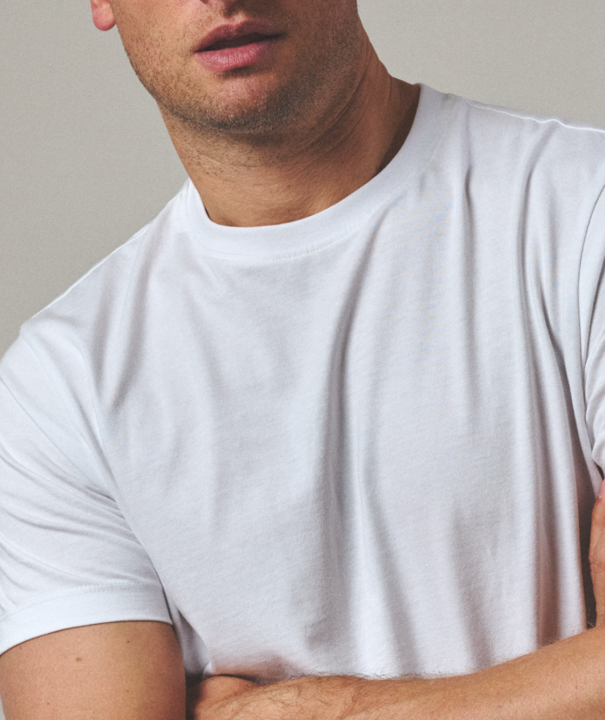 Man wearing a plain white t-shirt against a neutral background