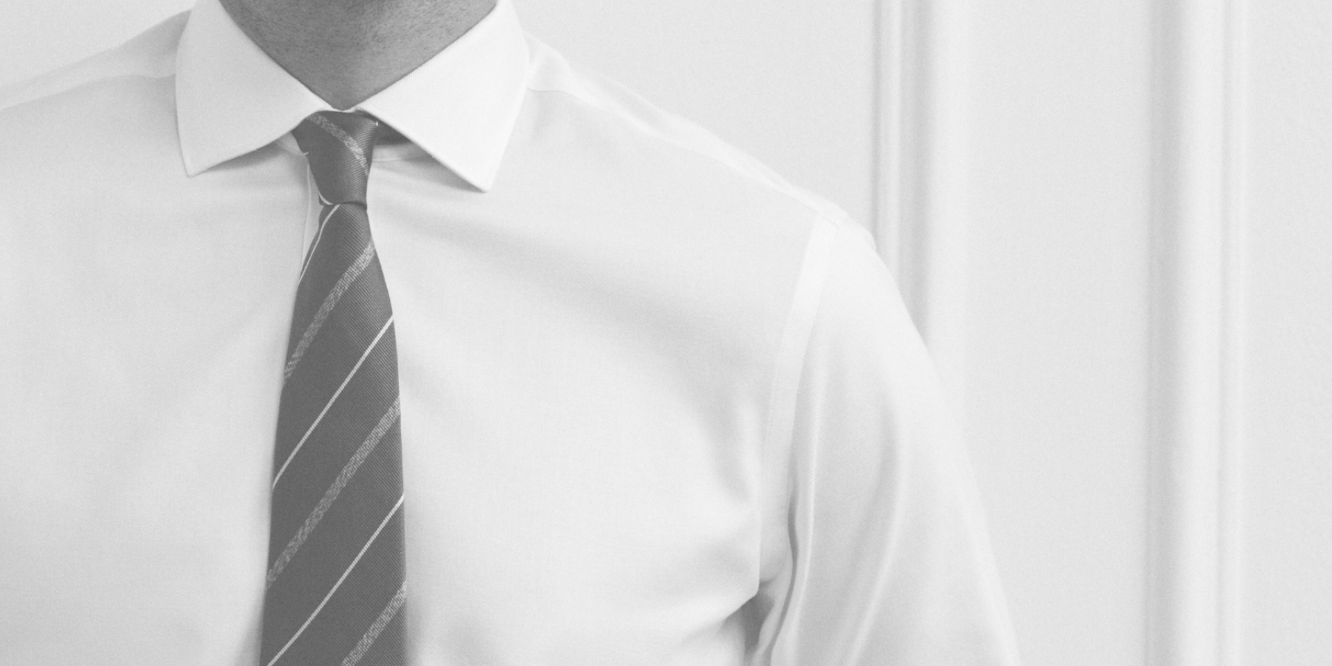 Close-up of a person wearing a white shirt and striped tie against a white background